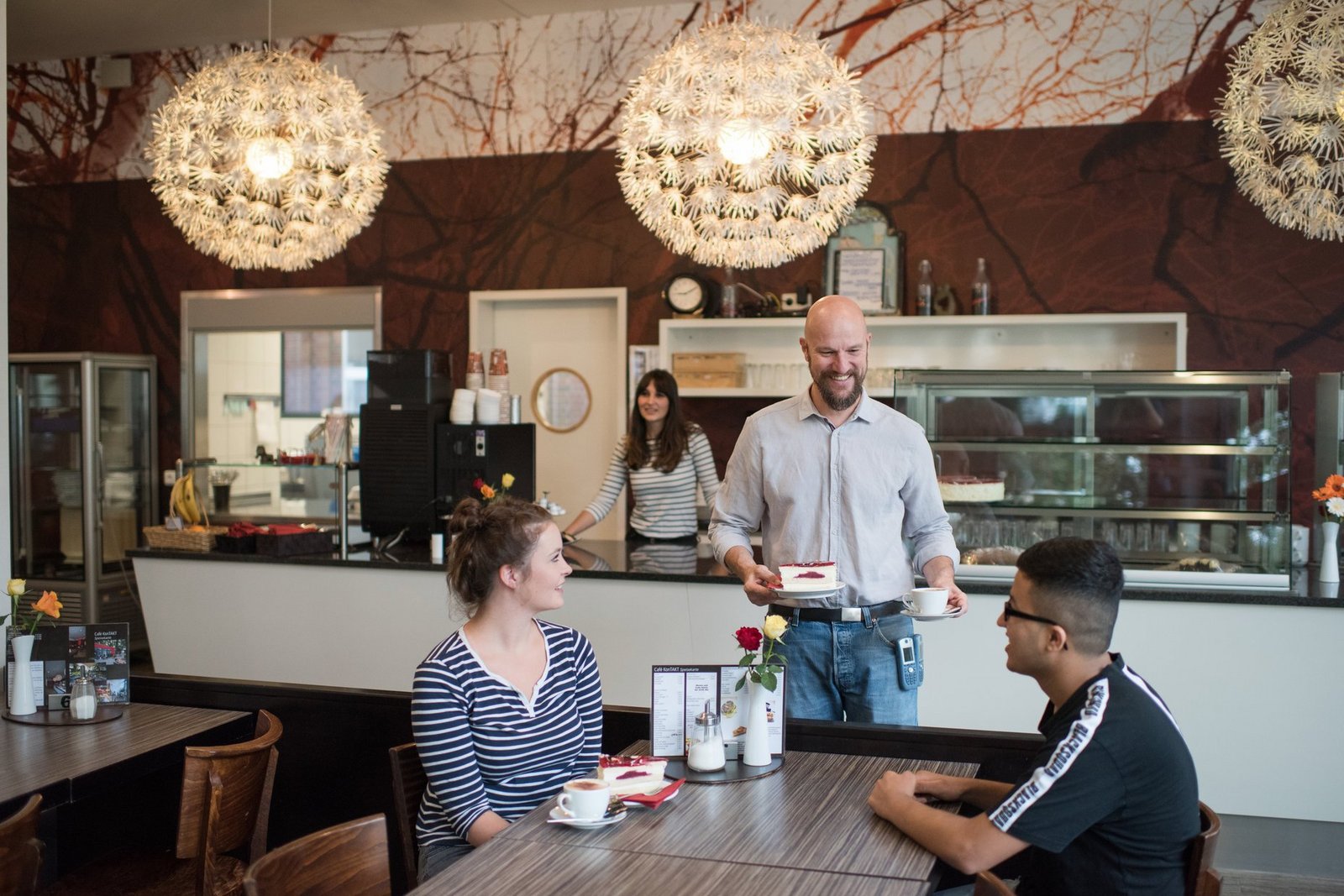 Bedienung zweier Gäste an einem Tisch im Café Kontakt